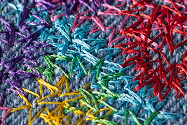 Close-up of the portrait showing the pixelated effect created by crossing stitch directions and intersecting colours